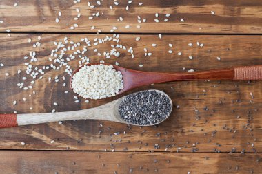 Tahta kaşıklardaki susam tohumları ve siyah chia tohumları kopya alanı ile üst görünüm