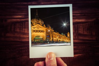 Geceleri Flinders Caddesi 'ndeki istasyonun anlık fotoğraf kartpostalını tutuyor. Melbourne, Avustralya. Kopya alanı ile güzel zamanların hatıra defterini gezdir