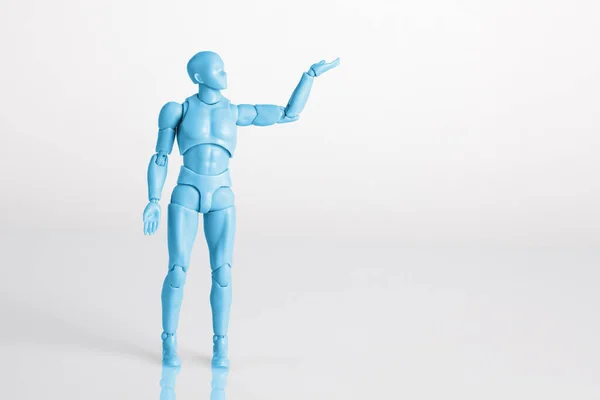 Niebieska Męska Figurka Stojąca Białym Refleksyjnym Stole Trzymająca Jedną Rękę — Zdjęcie stockowe