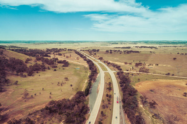Aerial view of cars and trucks driving on Hume Highway among Australian countryside.