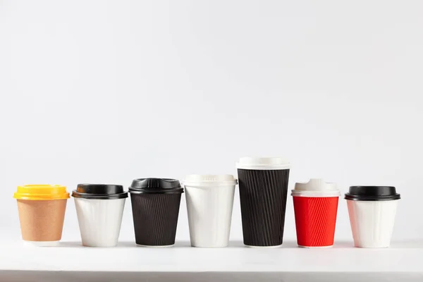 可处置的咖啡杯 不同的颜色和尺寸 一排排 白色背景 有复制空间 — 图库照片