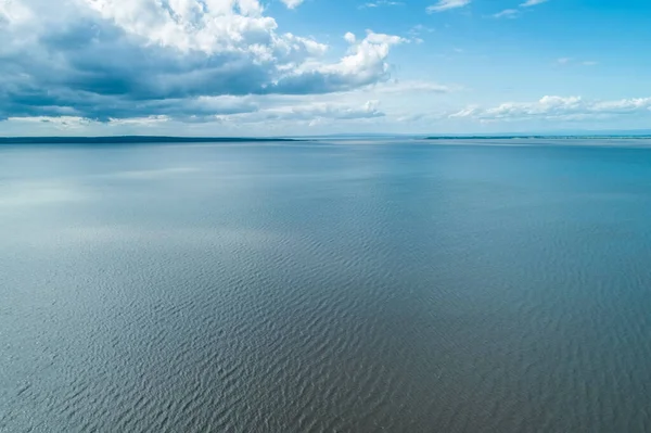 Minimalist landscape of water ripples and white clouds