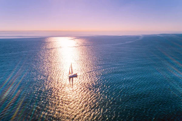 Sailboat in the ocean with strong sunset backlight - minimalist aerial seascape with copy space