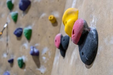 Spor salonunda, sığ bir alan derinliği olan bir duvarda büyük bir tırmanış tutuşu.