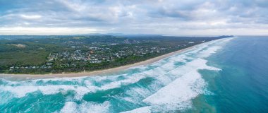 Suffolk Park 'ın banliyösü ve karamsar gökyüzünün altındaki okyanus plajı. Yeni Güney Galler, Avustralya