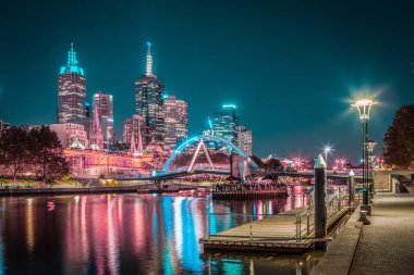 Melbourne CBD - APR 17 2016: Yarra nehri ve Flinders sokak istasyonu üzerinde Southbank yaya köprüsü ile gece manzarası.