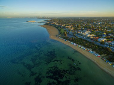 Brighton Sahili sahil şeridinde gün doğumunun hava görüntüsü, plaj kutuları ve uzaktan kumandalı CBD. Melbourne, Victoria, Avustralya.