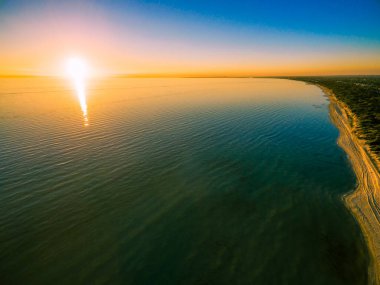 Okyanusun ve kıyı şeridinin üzerinde güzel bir gün batımı