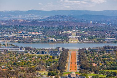 Ainslie Dağı 'ndan Canberra manzarası - ANZAC Geçidi, Parlamento Binası ve arkasında dağlar olan modern mimari. ACT, Avustralya