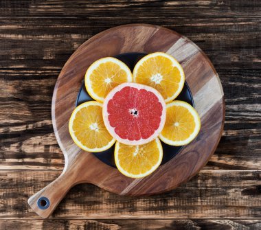 Çiçek şeklinde bir tabakta portakal ve greyfurt dilimleri sıralanmış. Üst görünüm