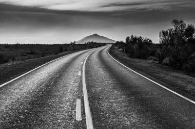 Güney Avustralya taşrasındaki kırsal yol siyah beyaz güzel bir dağ zirvesine çıkıyor.