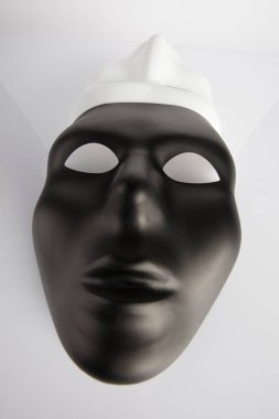 Siyah ve beyaz maskeler beyaz yansıtıcı arka planda birleşti. Geniş açı, dikey görüntü, üst görünüm.