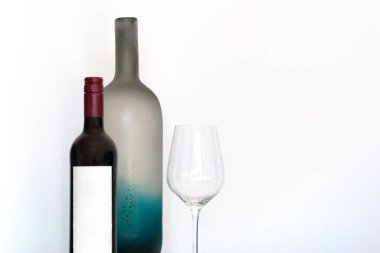 Boş etiketli şarap şişesi, şarap kadehi ve dekoratif buzlu cam şişe beyaz arka planda fotokopi alanı ile