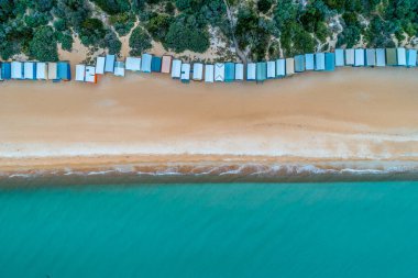 Bathing boxes, sandy beach, and turquoise ocean water - aerial top view clipart