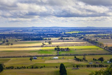 Avustralya 'da kırsal alan - bulutlu gökyüzünün altındaki yeşil tarlalar ve tepeler