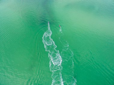 Turkuaz suda yarışan iki jet skinin hava görüntüsü.