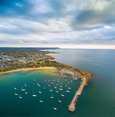 Güzel günbatımında demirli teknelerin, rıhtımın ve sahil şeridinin havadan görüntüsü. Mornington Yarımadası, Melbourne, Victoria, Avustralya