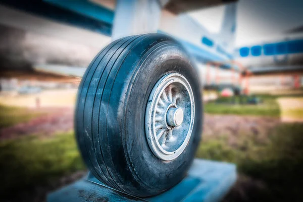 Old airplane landing gear wheel closeup on blurred background.