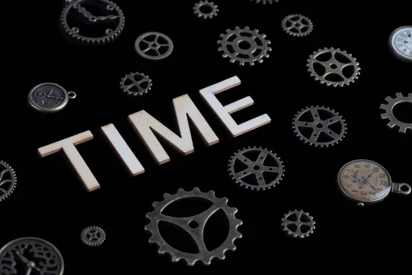 Concept of time depicted with cog wheels, watches and lettes isolated on black background