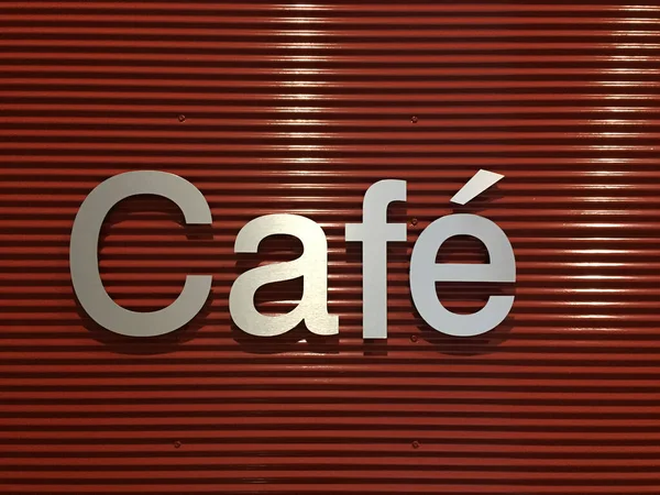 Stylish cafe sign on red metal background closeup