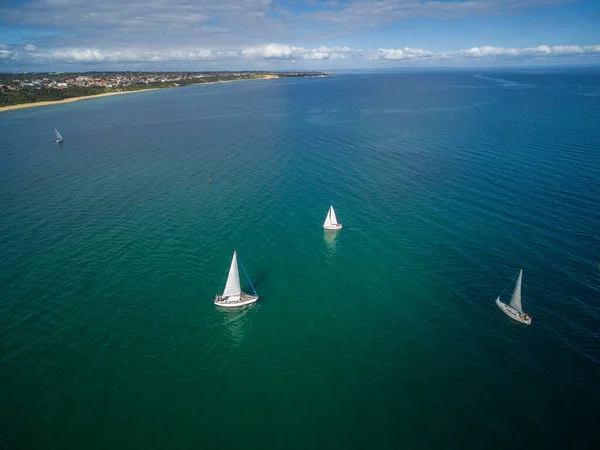 Aerial image of sailboats sailing in waters of Mornington Peninsula on sunny day