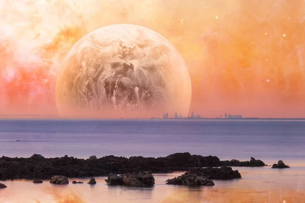 ファンタジーの風景 オレンジの空の前景に岩の形成と巨大な異星人の惑星と海を渡って近代的な都市のスカイライン この画像の要素はNasaによって提供されています — ストック写真