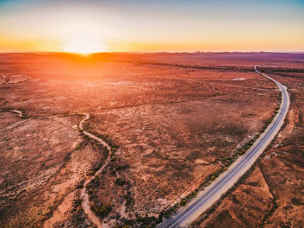 乾燥した土地と南オーストラリアで巻き田舎の高速道路の上にオレンジの夕日 — ストック写真