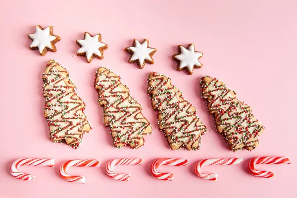 Christmas sweet foods - Christmas tree biscuits with candy canes arranged on pink background