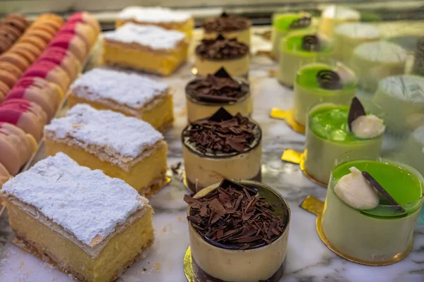Rows of decorative sweet dessert at a cafe counter with shallow focus
