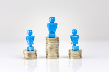 Bir erkek ve iki kadın heykeli bozuk para yığınlarının üzerinde duruyor. Gelir eşitsizliği kavramı.