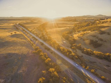 Aerial view of Hume Highway passing through scenic countryside at sunset in Australia clipart
