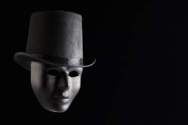 Siyah şapkalı siyah maskeli yüz, siyah arka planda izole edilmiş, fotokopi alanı olan. Anonimlik ve gizem kavramı