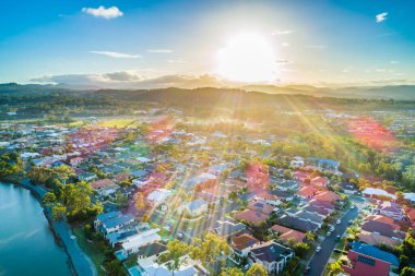 Varsity Lakes banliyösünün hava manzarası gün batımında güneş ışınlarıyla parlıyor. Gold Coast, Queensland, Avustralya