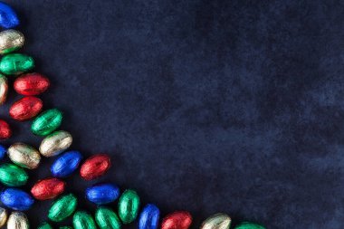 Renkli folyoya sarılı çikolatalı paskalya yumurtaları grunge arka planında fotokopi alanı ile