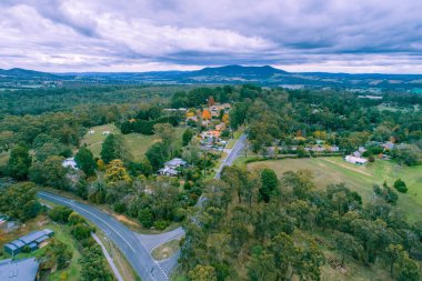 Kırsal yol ağaçların arasından geçerek Horison 'daki dağlara doğru gidiyor - hava manzarası