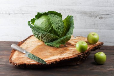 Üç yeşil elma ve mutfak bıçağıyla dolu bir lahana. Kabataslak ahşap doğrama tahtasının üzerinde.