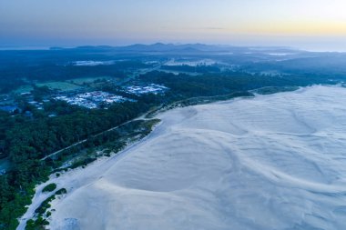 Güzel kum tepeleri ve okyanus kenarındaki tepeler şafakta. Anna Körfezi, Yeni Güney Galler, Avustralya