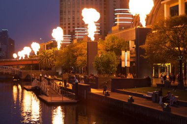 Melbourne CBD - APR 16 2016: Crown Casino fire show - powerful bright flames emitting from industrial structures with people watching. clipart