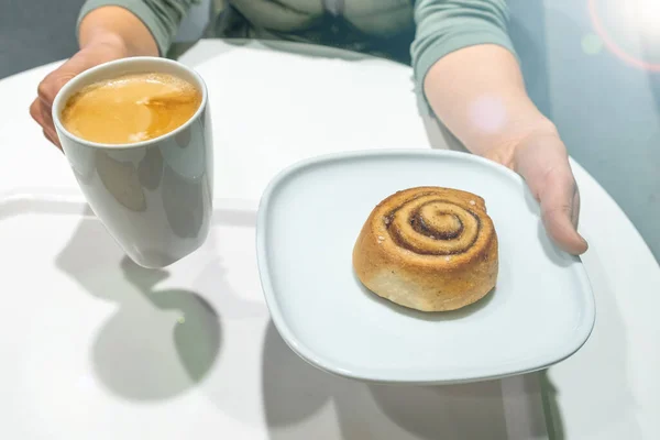 Kvinnliga Händer Håller Plattan Med Kanel Rulle Och Vit Kopp — Stockfoto