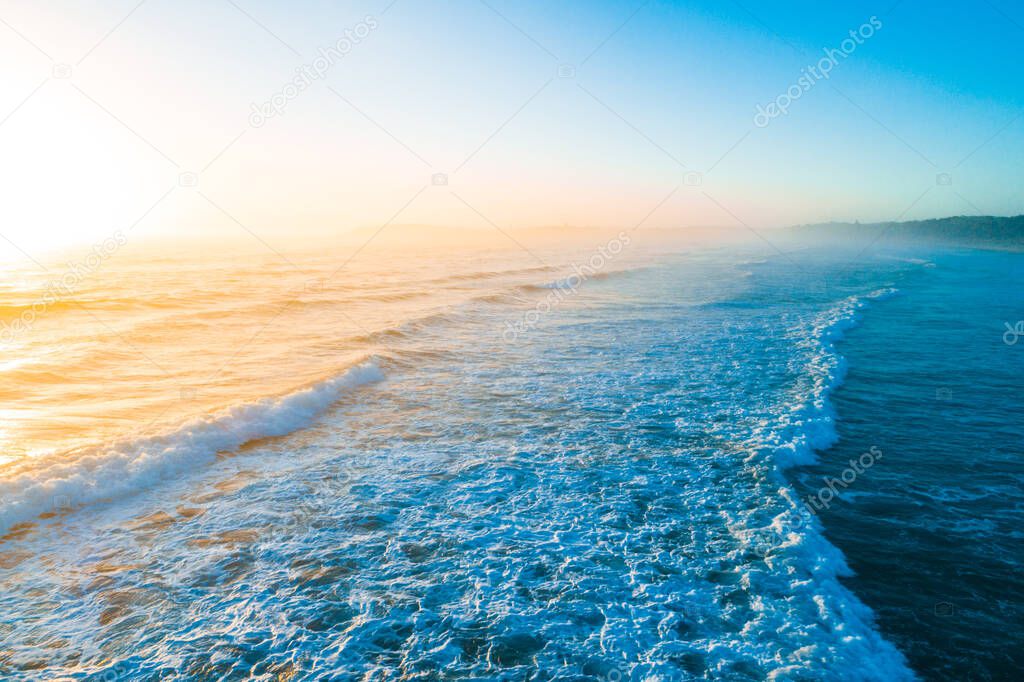 Beautiful golden sunrise over blue ocean waves with copy space