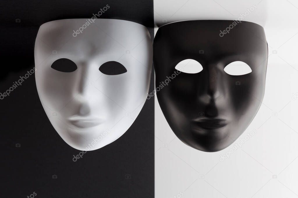 Black and white masks on contrasting backgrounds hanging from the ceiling.