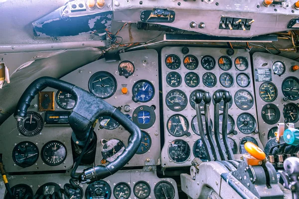 Closeup view of a yoke in old aircraft surrounded by many gauges, levers and switches