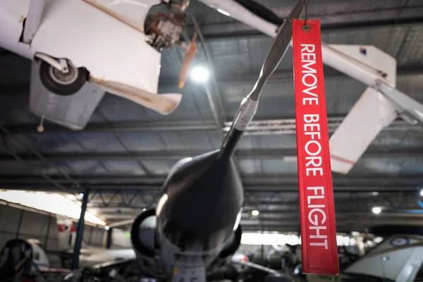 Remove Before Flight red ribbon hanging off fighter jet in hangar with shallow focus
