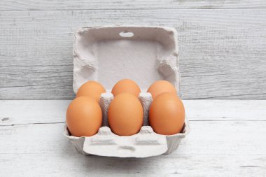 Altı paket yumurta beyaz ahşap masa üzerinde, fotokopi alanı ile.