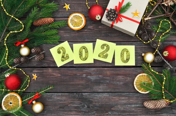 New Year holiday concept. Yellow sticky notes with numbers 2020 on a festive wooden background.