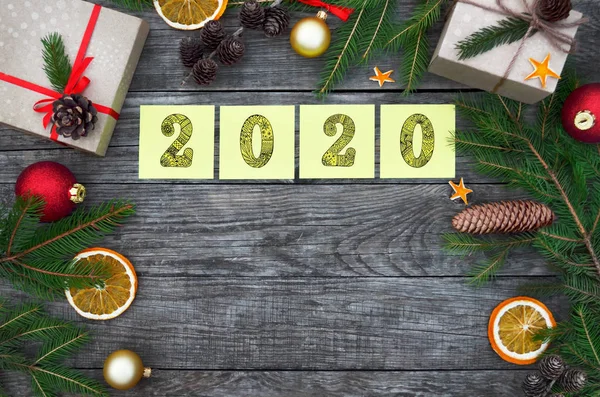 New Year holiday concept. Yellow sticky notes with numbers 2020 on a festive wooden background.