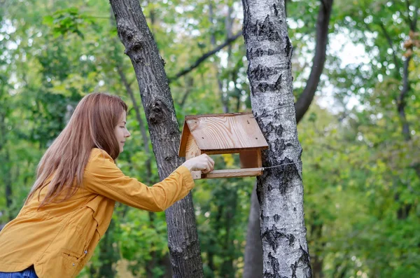 Young woman adds food to a bird feeder — Stock Photo, Image