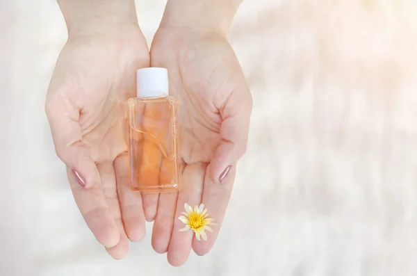 Kadın eli arka planda küçük bir şişe doğal kozmetik tutuyor. Doğal bitki bileşenlerine dayalı kozmetik ürünü. Güzellik ve sağlık konsepti