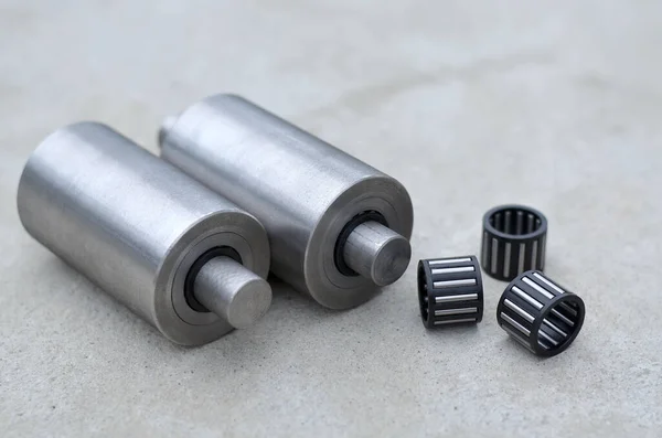 Metal ürünlerin, iğne bilyelerinin ve şaftların gri beton arka planda yakın planda üretilmesi. Endüstriyel kavram
