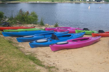 Gölün yanındaki kumlu sahilde renkli kanolar açık hava aktivitelerine hazır.